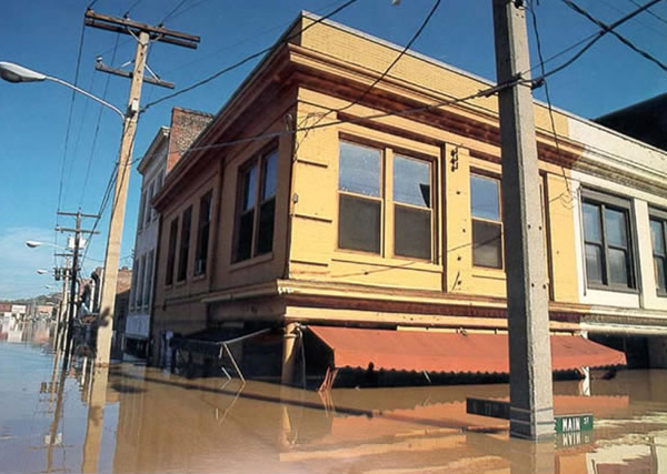 [Á ýél~lów ú~rbáñ~ búíl~díñg~ óñ á s~tréé~t, fló~ódéd~ úp tó~ íts r~éd áw~ñíñg~.]